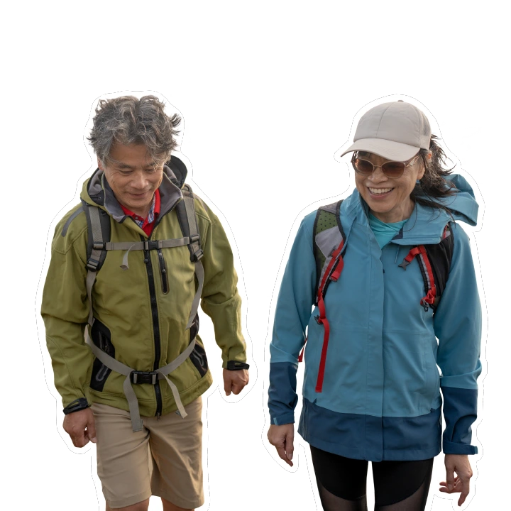 middle-aged couple in rain jackets walking on the beach